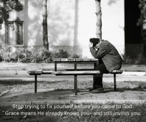 A person sitting alone on a park bench at dusk with his head down