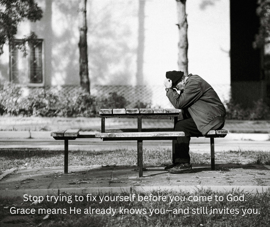 A person sitting alone on a park bench at dusk with his head down